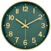 A round, dark green wall clock with gold-colored numbers and hands displaying a time close to 12 o'clock.