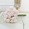 A bouquet of light pink silk peonies with green stems displayed on a white surface.