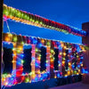 A long, colorful LED rope light is strung across a wooden fence at twilight.