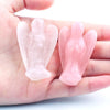 Hand-carved pink crystal figurine of an angel held in a person's hand.