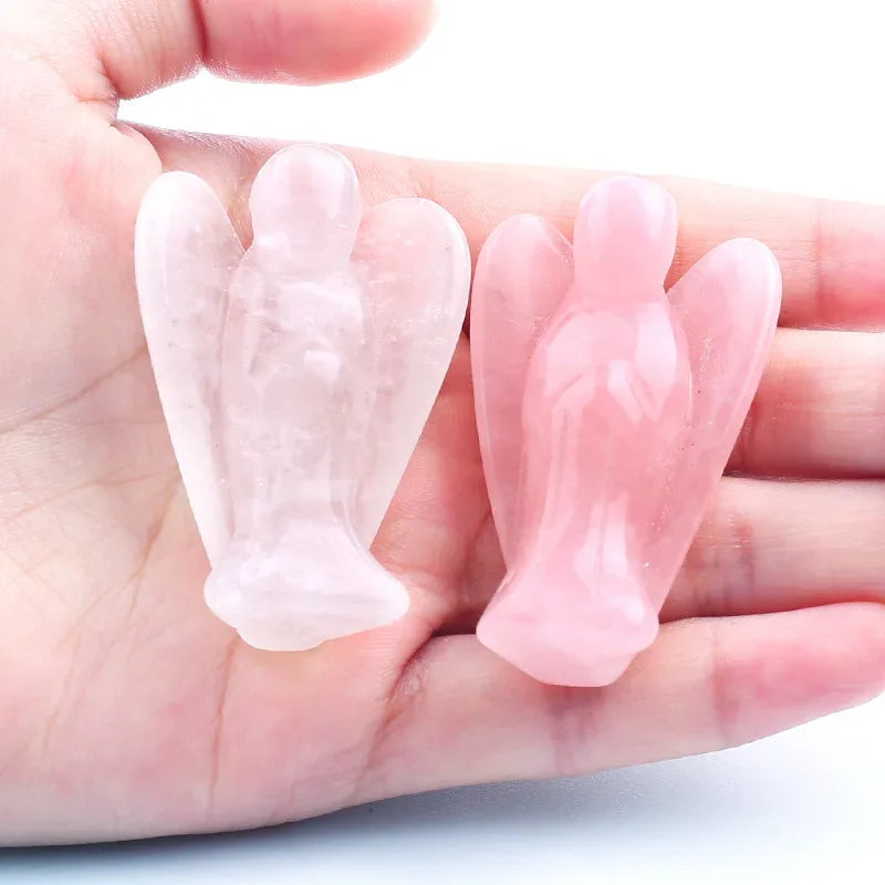 Hand-carved pink crystal figurine of an angel held in a person's hand.