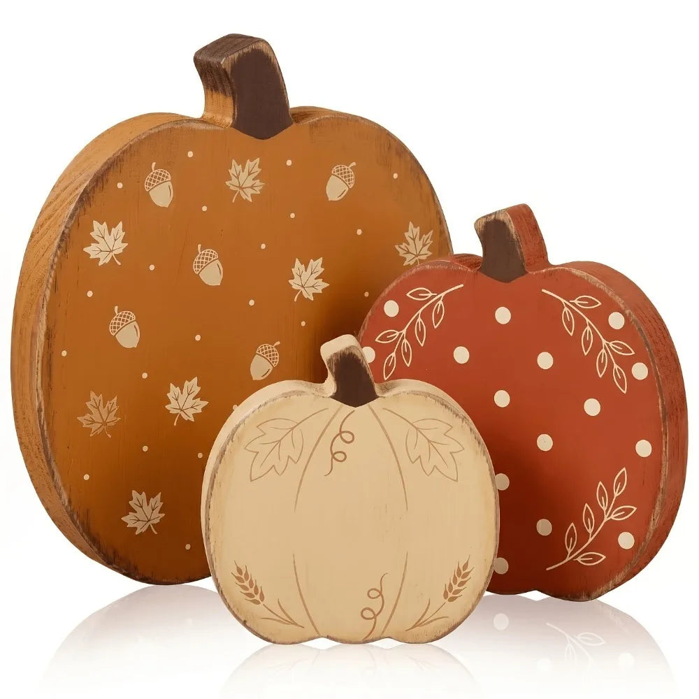 A set of three wooden pumpkin figurines in orange, terracotta, and cream colors for fall decor.