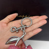 Silver keychain charm featuring a pink cherry bag pendant on a hand.