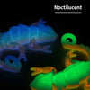 A close-up image of a noctilucent dragon lizard figurine glowing with blue and green light against a dark background.