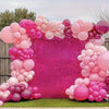 A vibrant balloon arch made of pink and magenta balloons for an event backdrop.