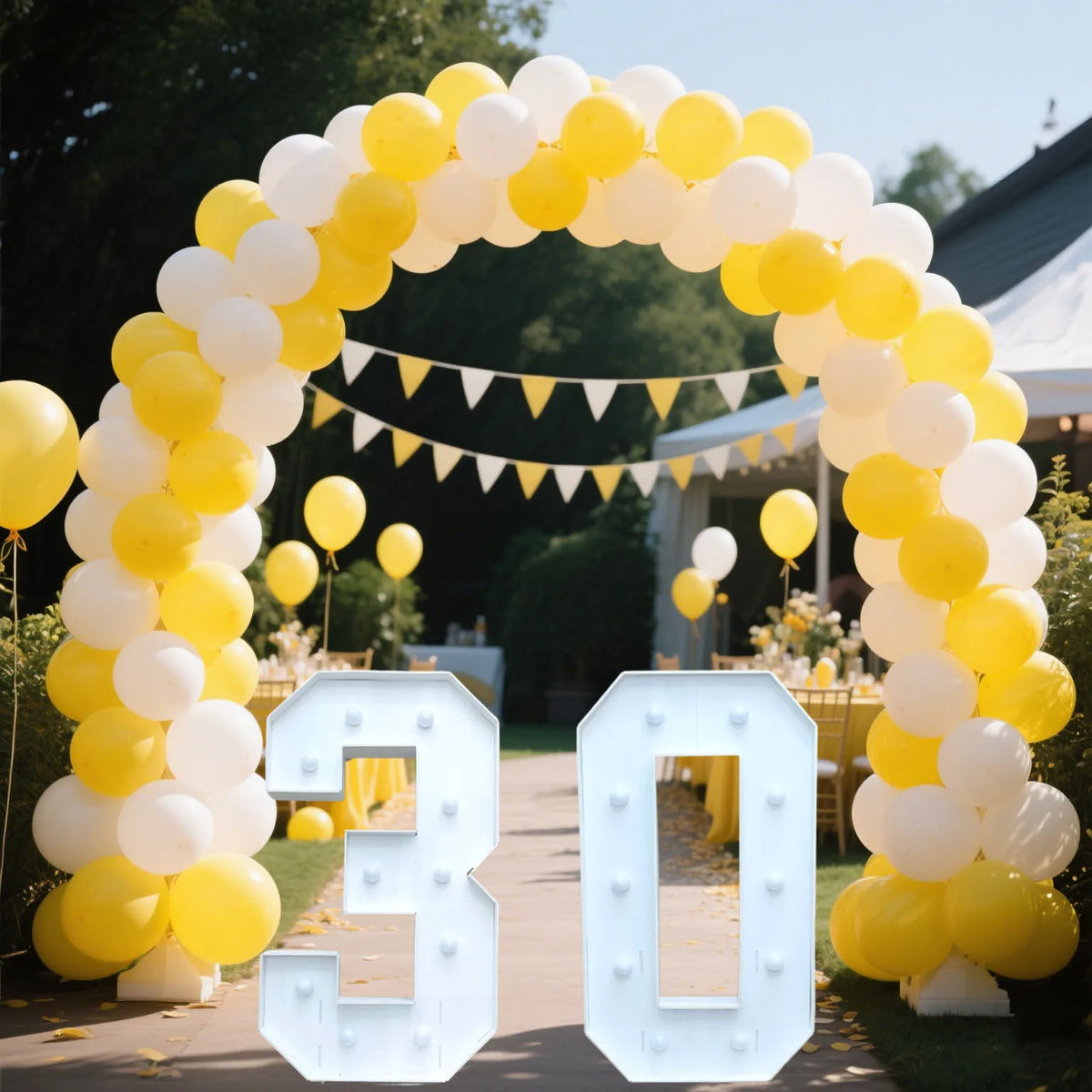 A large marquee sign shaped like the number 30 made of light-up acrylic letters surrounded by yellow and white balloons.