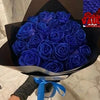 A bouquet of deep blue glitter artificial roses in a black box with a purple label