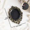 A vintage baroque resin hanging photo frame in black and gold on a white background.