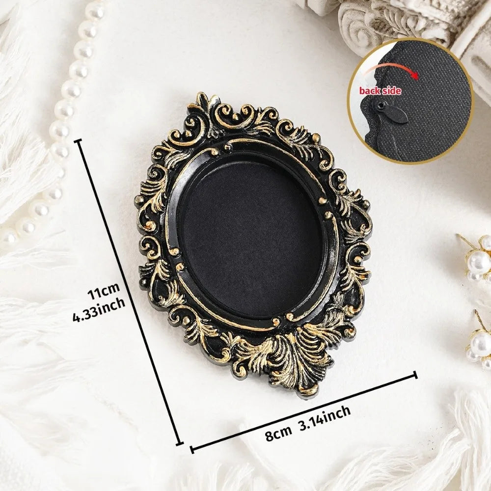 A vintage baroque resin hanging photo frame in black and gold on a white background.