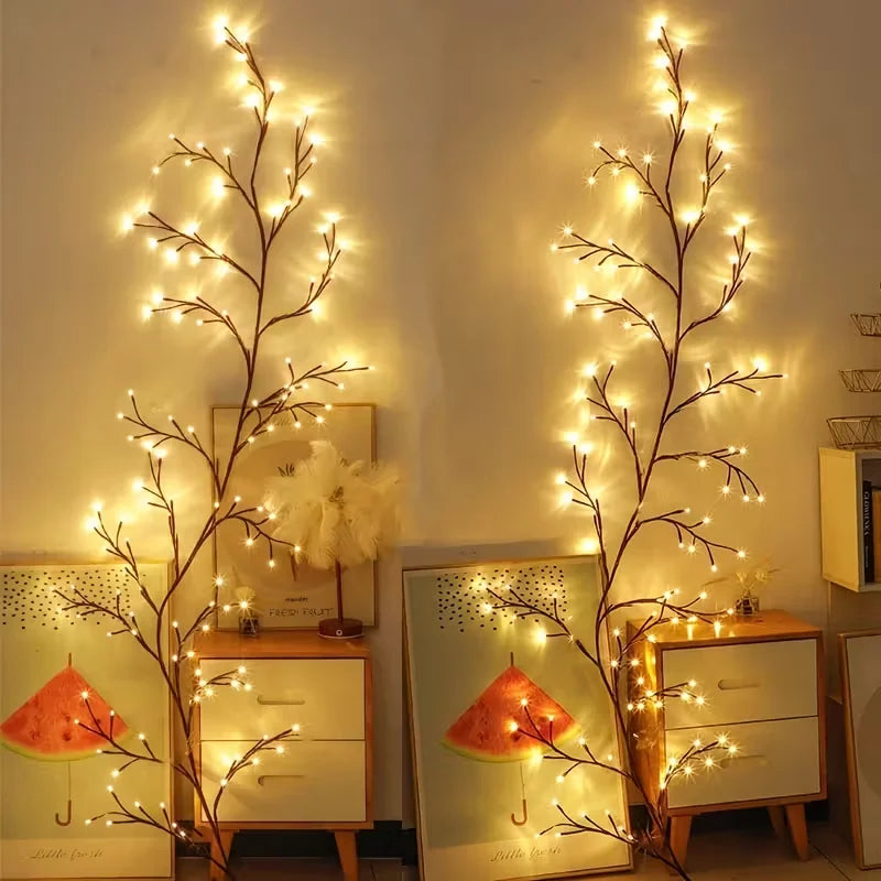 A decorative branch of willow vine lights illuminates a wooden cabinet and framed decor.