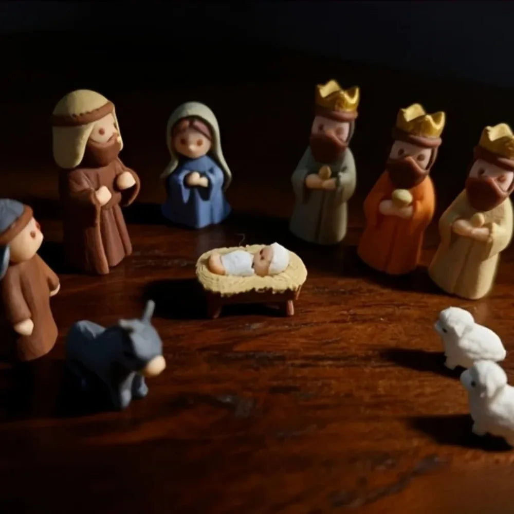 A dark wooden surface features a miniature nativity scene with several figures, including shepherds and a baby, arranged in a