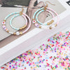 Gold and silver hoop earrings with beaded chains and colorful glass rice beads
