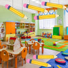 Colección de globos de lápiz inflables gigantes en amarillo y rosa decorando un aula o área de juegos.