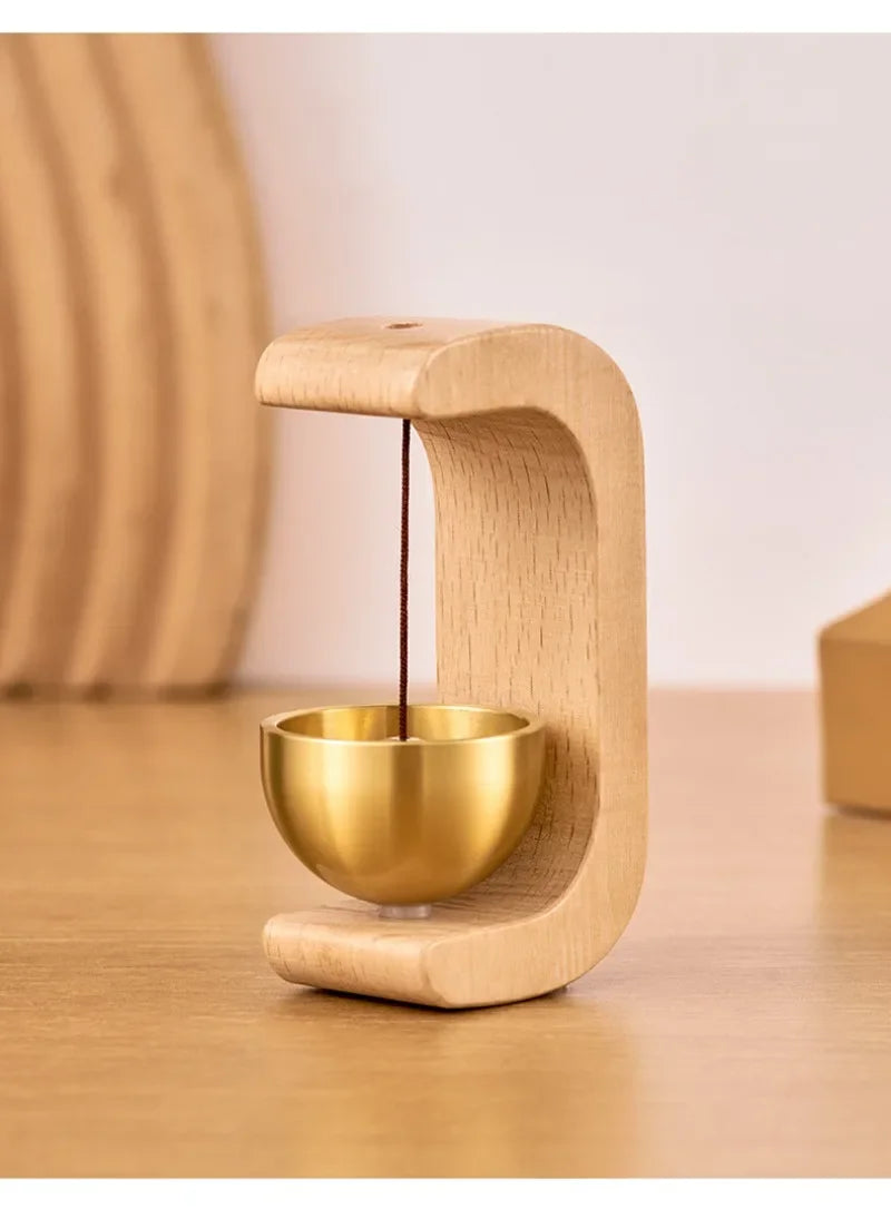 A wooden doorbell featuring a copper bell suspended by a string, designed for magnetic use.