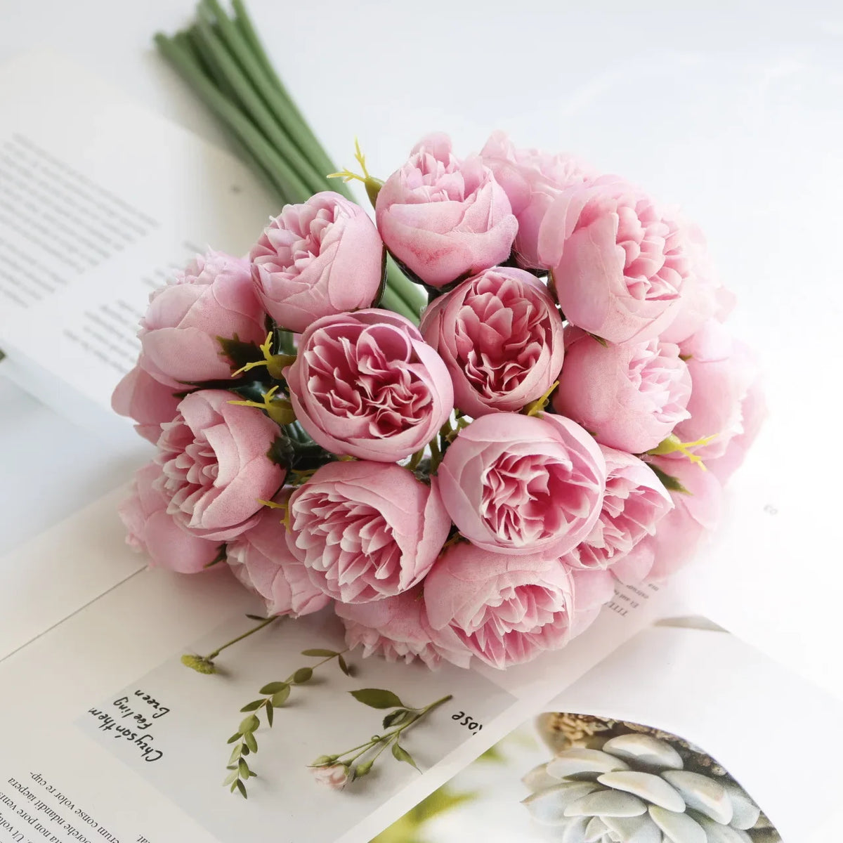 A bouquet of artificial pink peony silk flowers arranged on a white background.