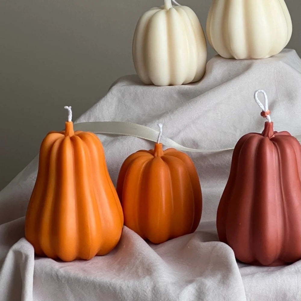 A collection of smooth silicone pumpkin molds in shades of orange and pink resting on white fabric.
