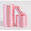 Pink silk satin ribbons rolled into spools and a pair of ribbon scissors