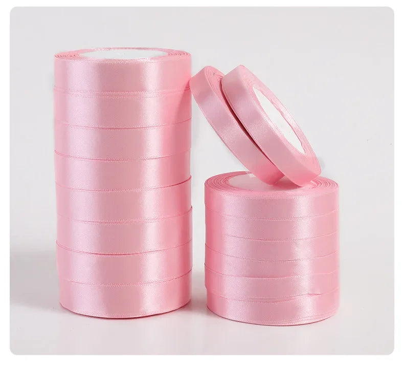 Pink silk satin ribbons rolled into spools and a pair of ribbon scissors