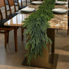 An artificial Norfolk pine garland with warm white lights displayed on a wooden table.