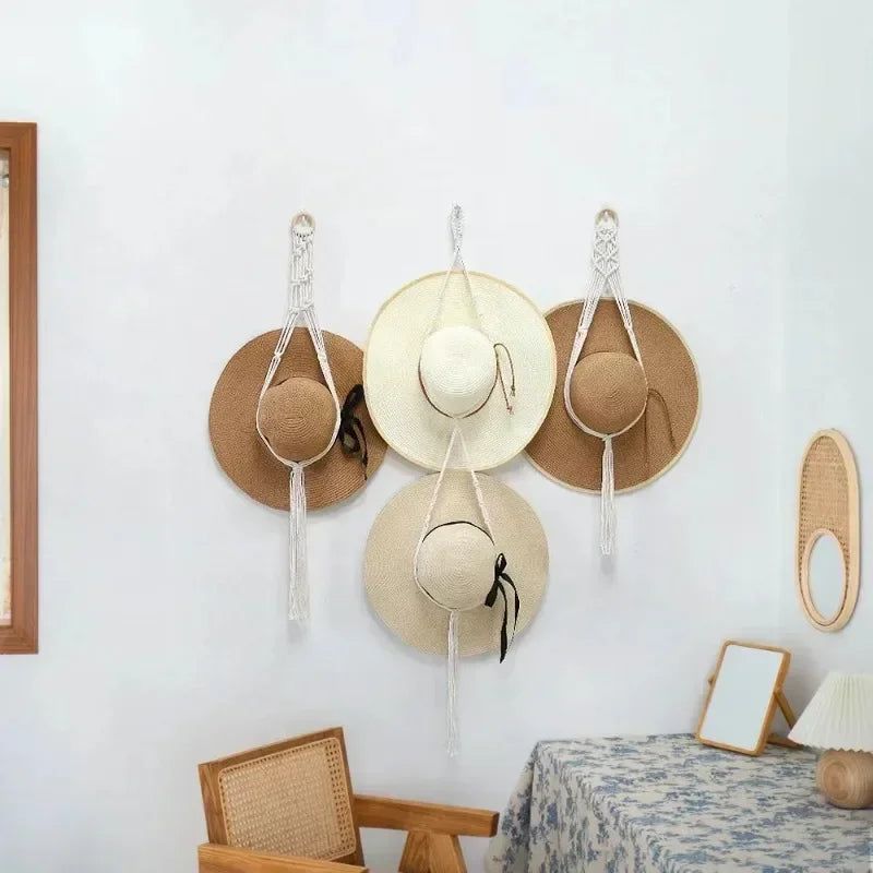 Boho wall hanging featuring three macrame hat organizers with wooden dowels mounted on a white wall.