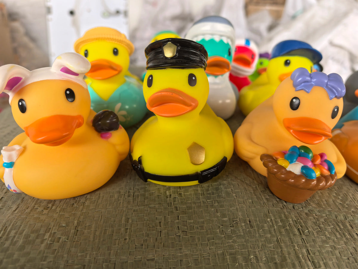 A collection of yellow rubber duck bath toys, including one with a black hat and another with colorful accents.