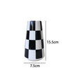 A ceramic tabletop vase with a black and white checkered pattern, shown from the side.