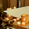 A wooden tray holds several natural beeswax tealight candles lit, creating a warm ambiance.