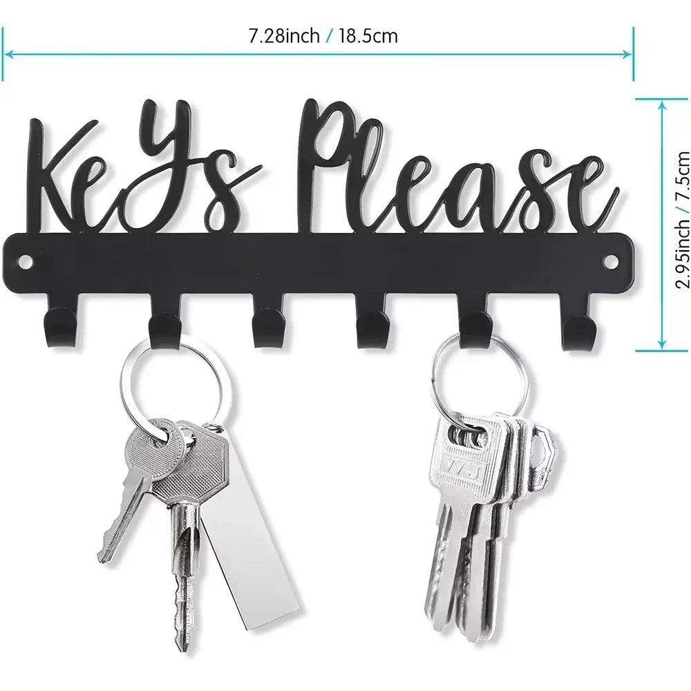 Black wall-mounted metal key holder with hooks featuring a decorative sign and multiple key rings.
