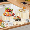 A white folding dessert table display stand featuring cupcakes and a tiered cake on a wooden surface.