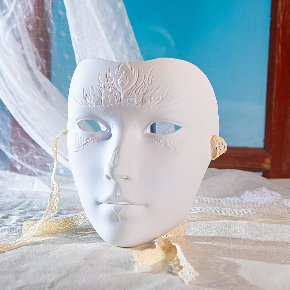 A white, sculpted masquerade mask with intricate tree-like designs is displayed on a light fabric surface.