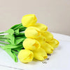 Un ramo de tulipanes de PU artificiales de color amarillo brillante, dispuestos sobre una superficie blanca.