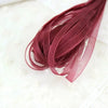 A bundle of deep burgundy decorative fishtail yarn ribbon laid on a white textured cloth.