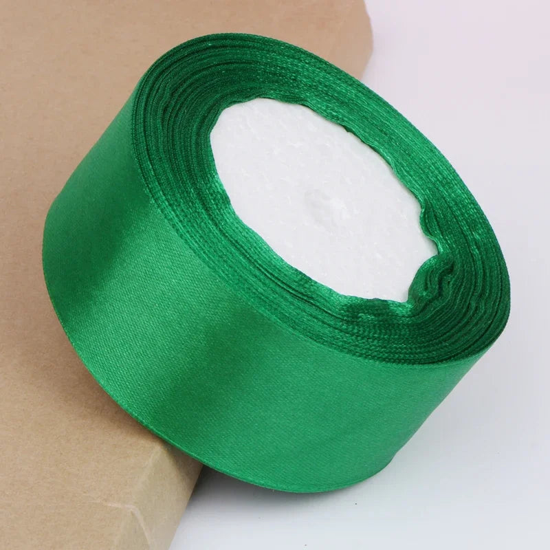 A roll of emerald green satin ribbon with a white center, shown against a brown paper background.