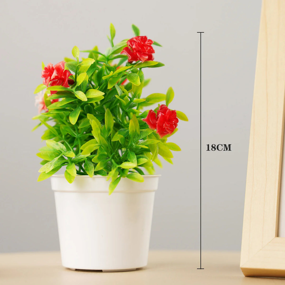 A vibrant artificial bonsai tree with bright green leaves and red flowers in a white pot.