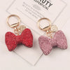 A pair of sparkling red and pink rhinestone bow keychains displayed on a white background.