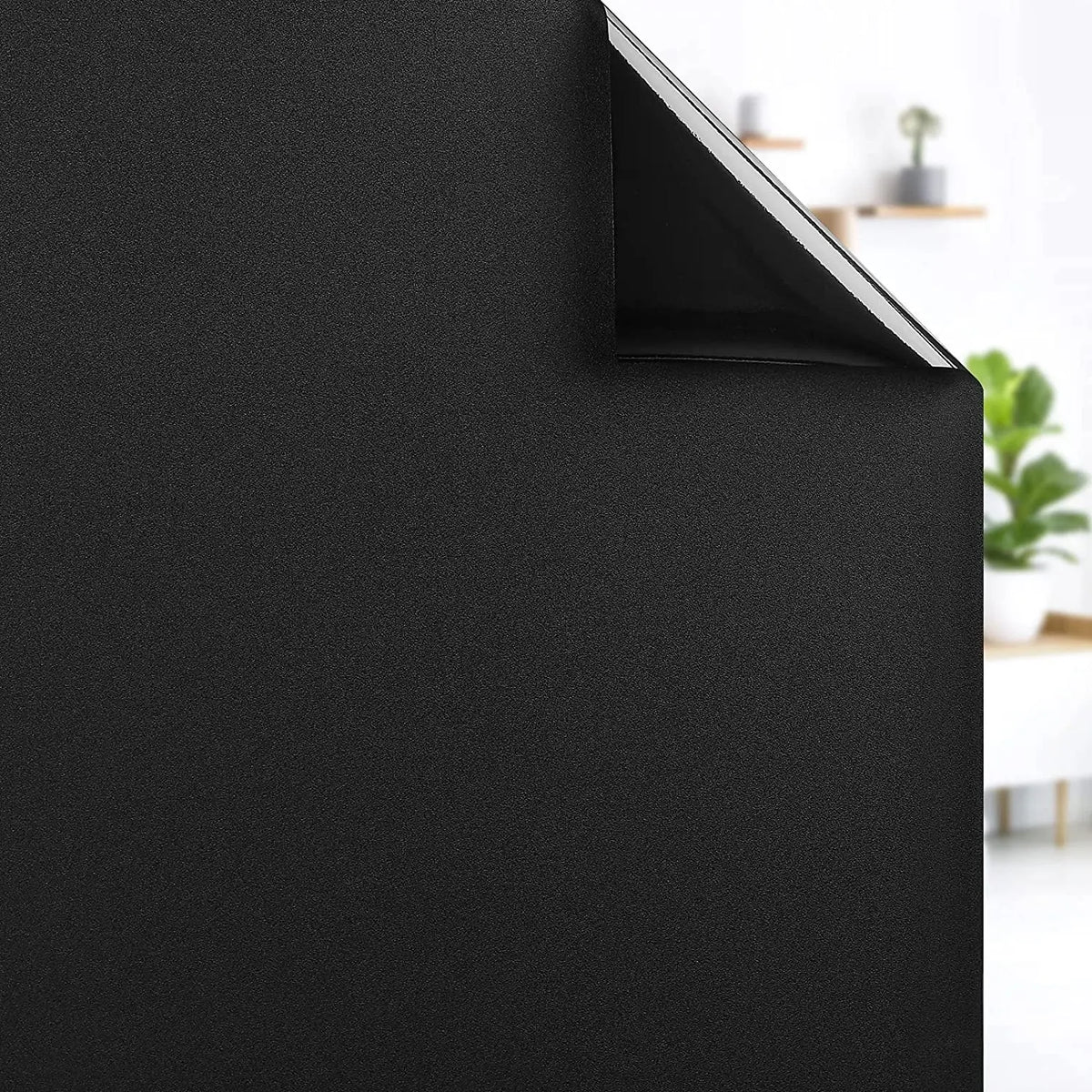 A close-up view of a black window privacy film being applied to a window surface.