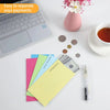 Colorful side-loading cash envelopes for budgeting and saving placed on a white surface next to a laptop.