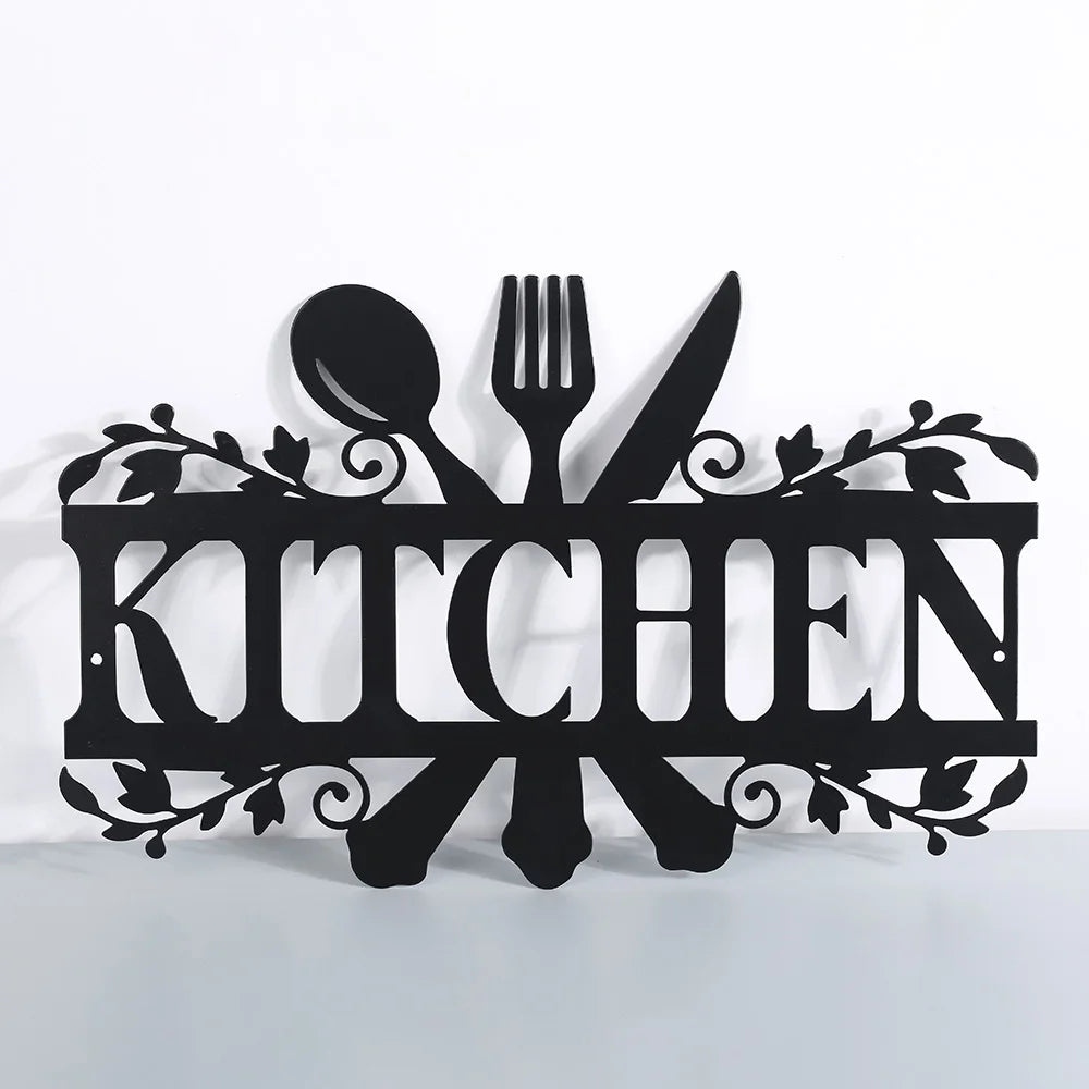 A black metal word sign spelling 'KITCHEN' featuring silhouette cutouts of a spoon, fork, and knife for kitchen wall decor.