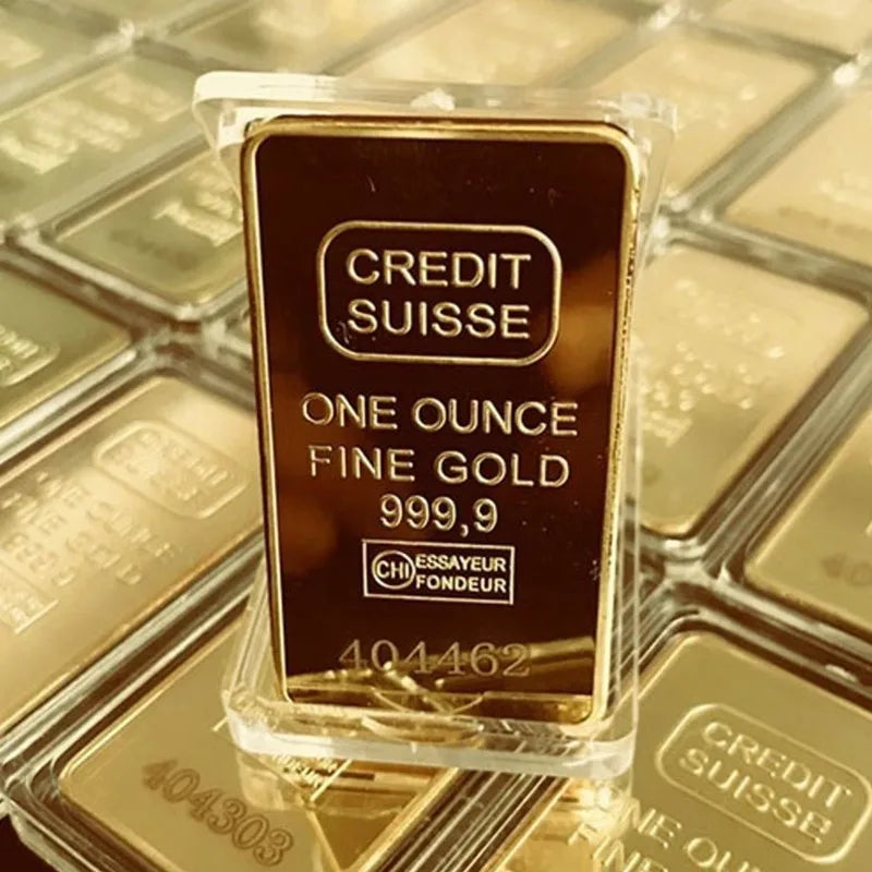 A rectangular gold-colored bullion ingot labeled Credit Suisse One Ounce Fine Gold 999.9 inside clear plastic packaging.