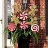 A festive arrangement of four gold gingerbread men and four red and white striped peppermint round ornaments on a green wreat