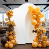 A bright yellow balloon arch backdrop decorated with yellow flowers and greenery for a wedding or party.
