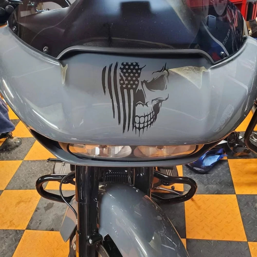 A close-up of a motorcycle fairing featuring a black American flag skull decal.