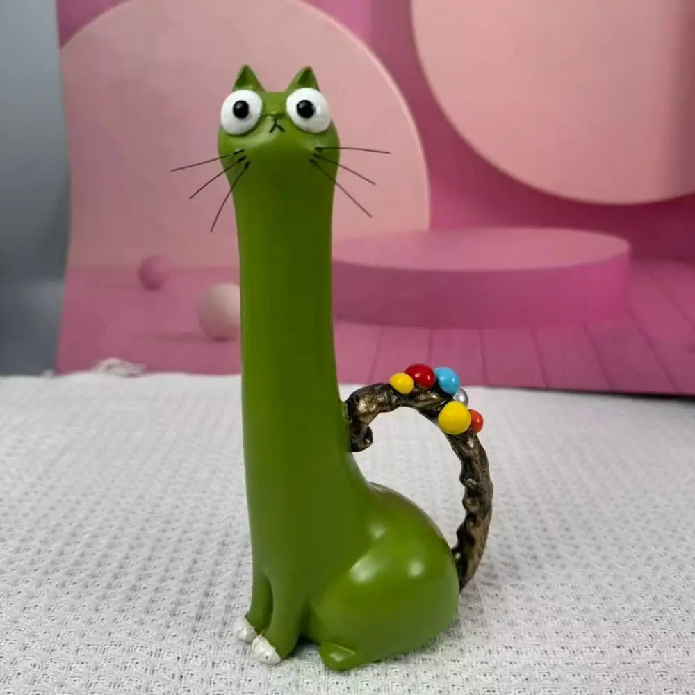 A green cat-shaped resin vase with large eyes and a vine-like handle sits on a white surface.