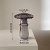 Vase décoratif en verre transparent à forme de champignon, large en haut et étroit en bas, sur fond blanc.