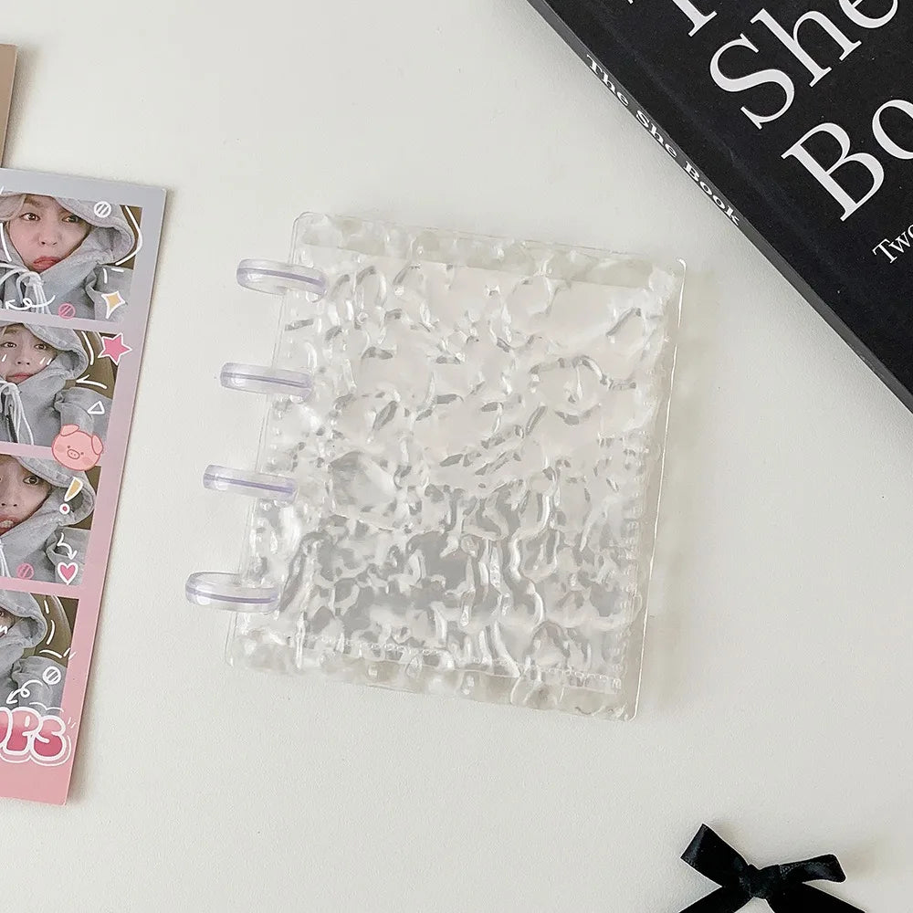 A clear transparent photocard album featuring a mushroom hole design resting on a white surface.