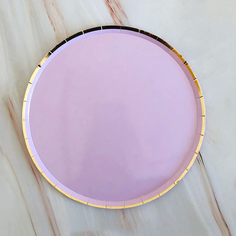 A round, light purple plate with a gold rim is shown on a white marble surface.