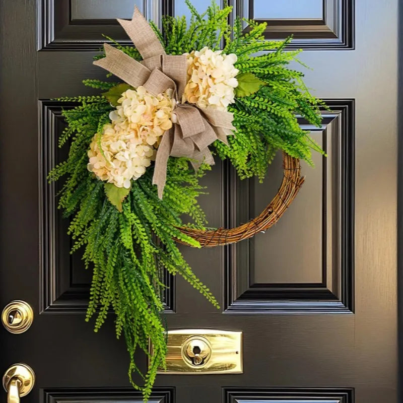 Rustic hydrangea wreath with a bow featuring white flowers and green foliage mounted on a dark door.