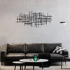 A modern living room features a dark leather sofa and a black geometric metal wall art sculpture above it.