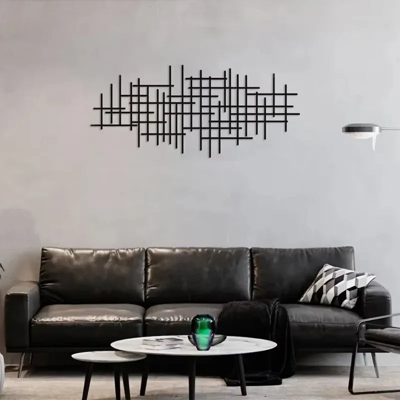 A modern living room features a dark leather sofa and a black geometric metal wall art sculpture above it.