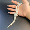 Une figurine de dragon peinte à la main ressemblant à un petit serpent est tenue dans la main d'une personne.